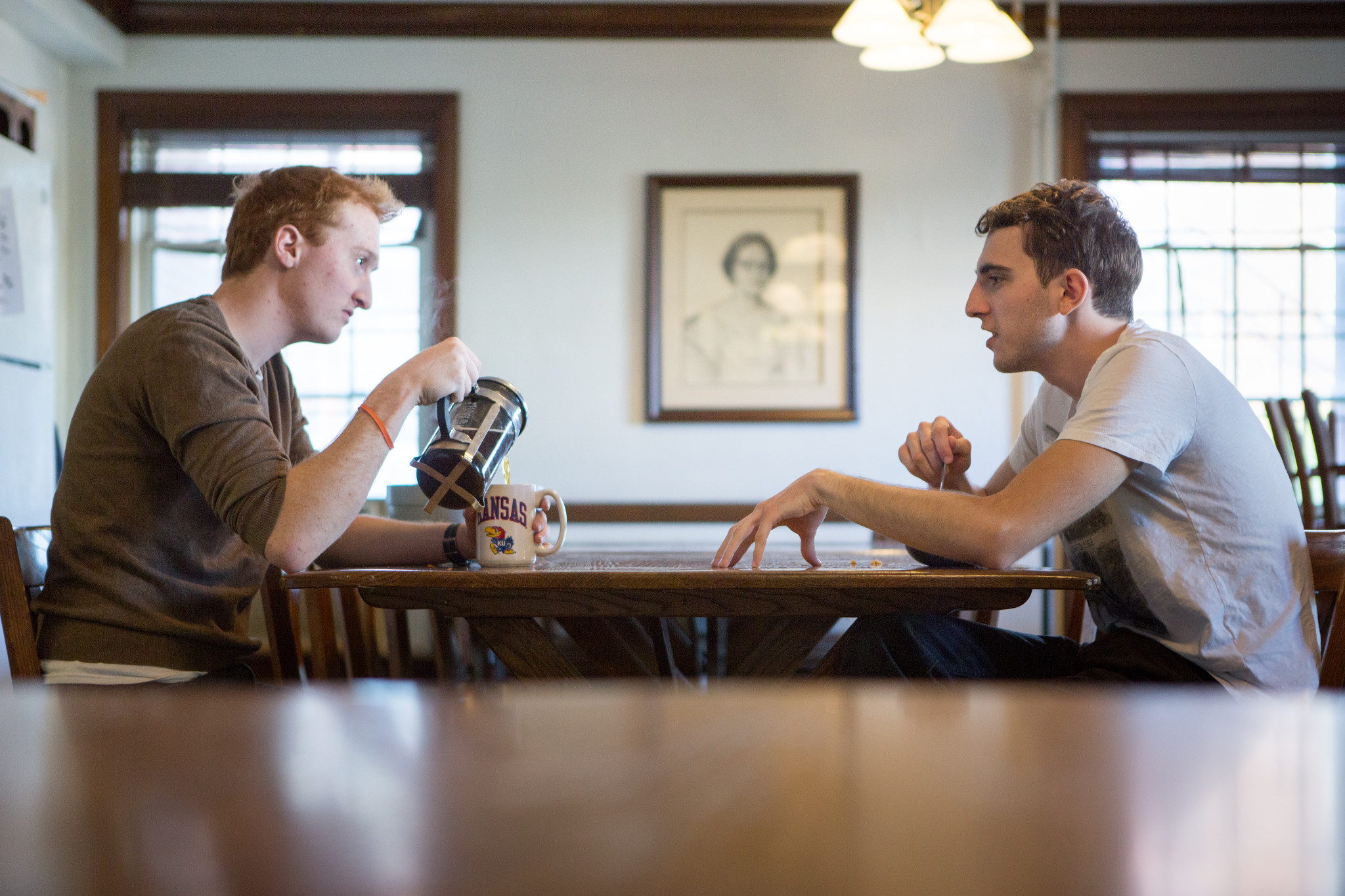Two individuals drink coffee and talk at the Men's Battenfeld Scholarship Hall.